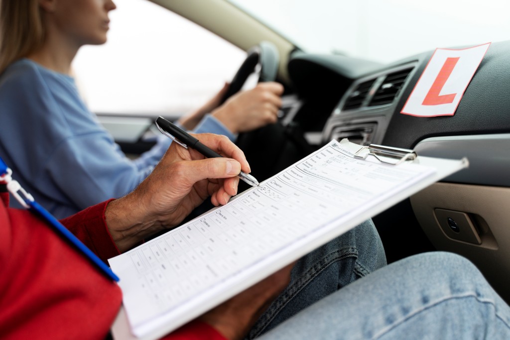 A learner driver studying the RSA driving test questions and answers with an examiner during under the bonnet checks.